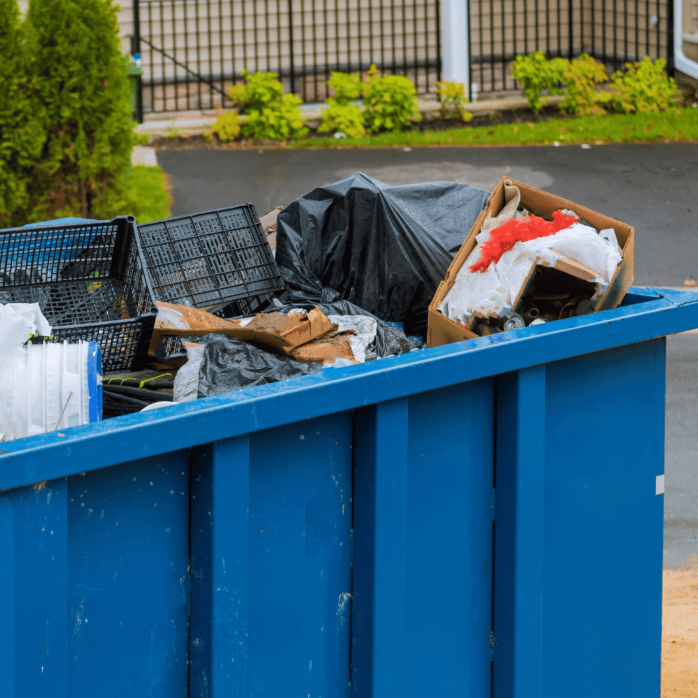 A blue dumpster with junk in it